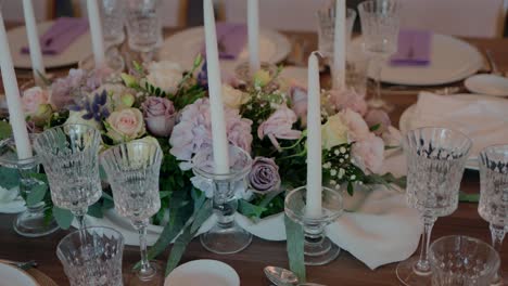 elegant table setting with crystal glasses, floral centerpiece, and tall white candles