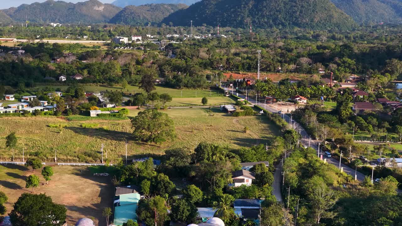 Uma filmagem de drone em um ângulo alto sobrevoa uma arquitetura vibrante em forma de domo, aninhada em paisagens tropicais verdejantes.