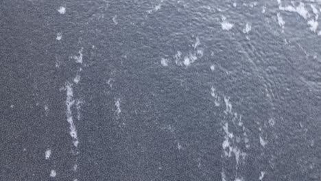 close-up of sea foam and water on dark sand