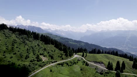 aerial reveal of meandering road vantage viewpoint lookout in mountains of french alps with mont blanc massive and eternal snow tops in the background
