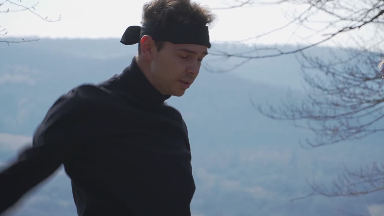A vibrant stock image of a person in a sleek black outfit performing a stretch exercise outdoors against majestic mountains and lush trees. Ideal for fitness, wellness, and adventure campaigns.