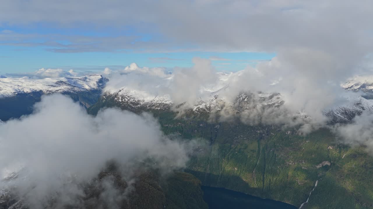 Un drone capture des sommets alpins enveloppés de nuages doux dans le ciel norvégien