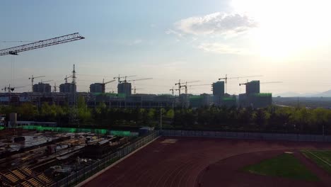 Aerial-drone-ascent-revealing-cranes-at-the-construction-site-of-Nanhai-New-District,-China