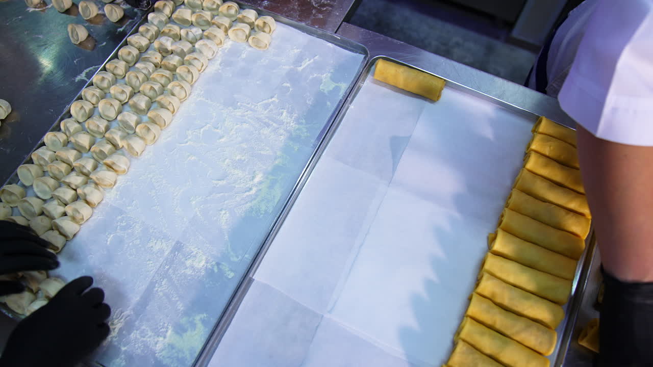 Chefs lay the ready-made food on the metal trays. Semi -cooked ravioli and stuffed crepes gathered together. Top view.
