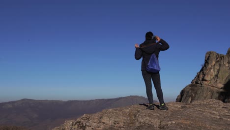 a lonely girl fixing her scarf and hair as she is looking at a mountain range in the distance