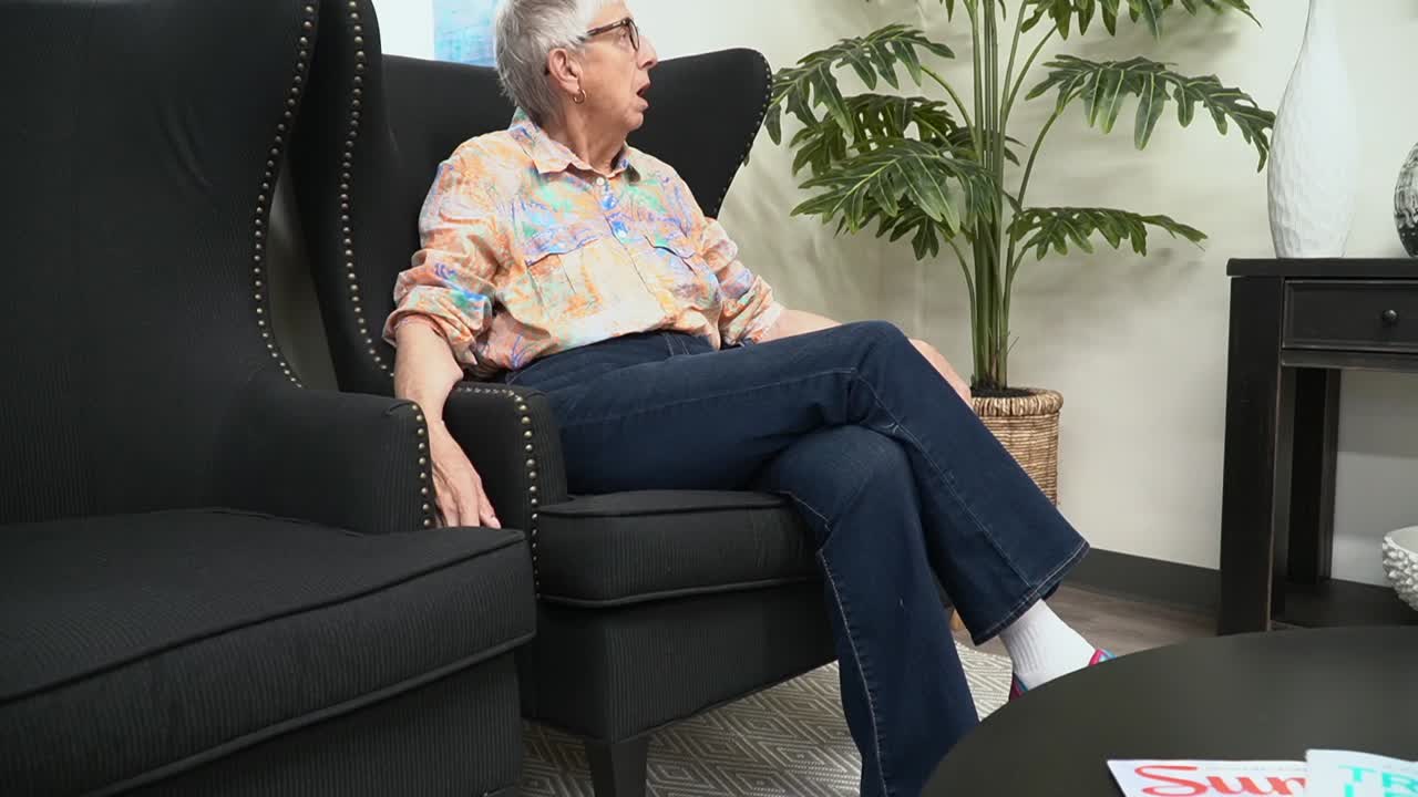 사무실에서 대기실에 앉아 있는 늙고 회색 머리의 여성을 향해 이동