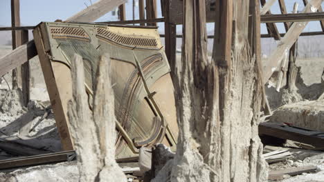 rubble from house fire damage, wood and broken piano, lie in the arid abandoned desert