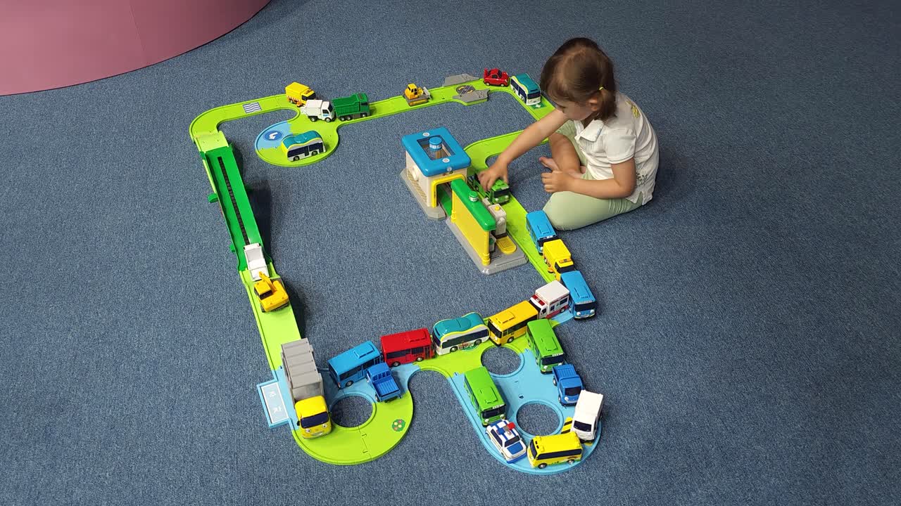 adorable niña jugando con coches de juguete en movimiento autobús en la rampa de la carretera construida autopista