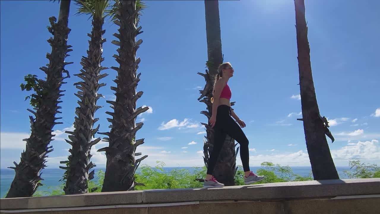 mujer caminando por el océano con palmeras