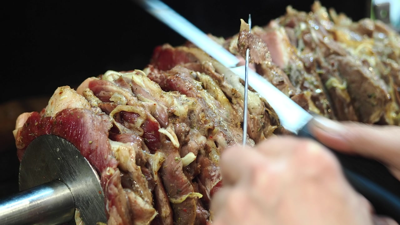 Chef Slicing Marinated Meat from a Doner Kebab Skewer