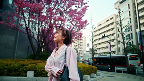 woman walking under cherry blossoms in a japanese city