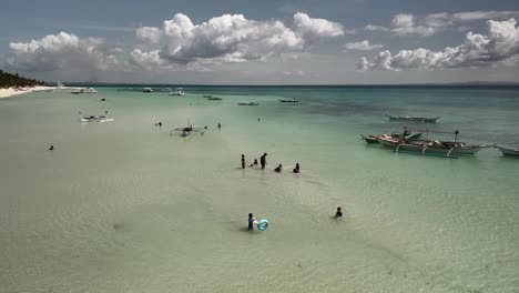 fishing boats and children playing at beach in bantayan island, cebu, philippines. drone shot