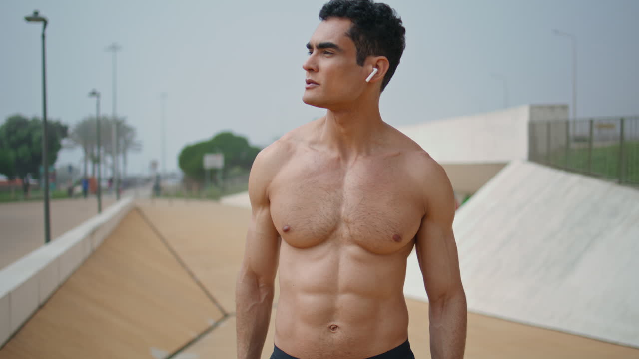 hombre muscular comprobando el rendimiento del rastreador. corredor en topless descansando usando inteligente