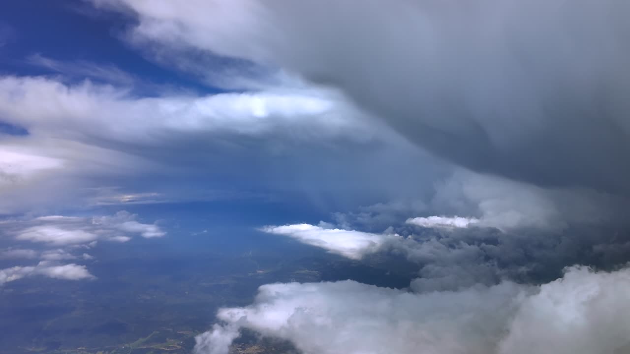 An aerial view of a massive storm cumulonimbus cloud, taken from a jet cockpit flying near the top.