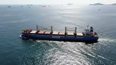 aerial view of a cargo ship navigating through tranquil waters surrounded by islands and other vessels, showcasing maritime transportation and trade