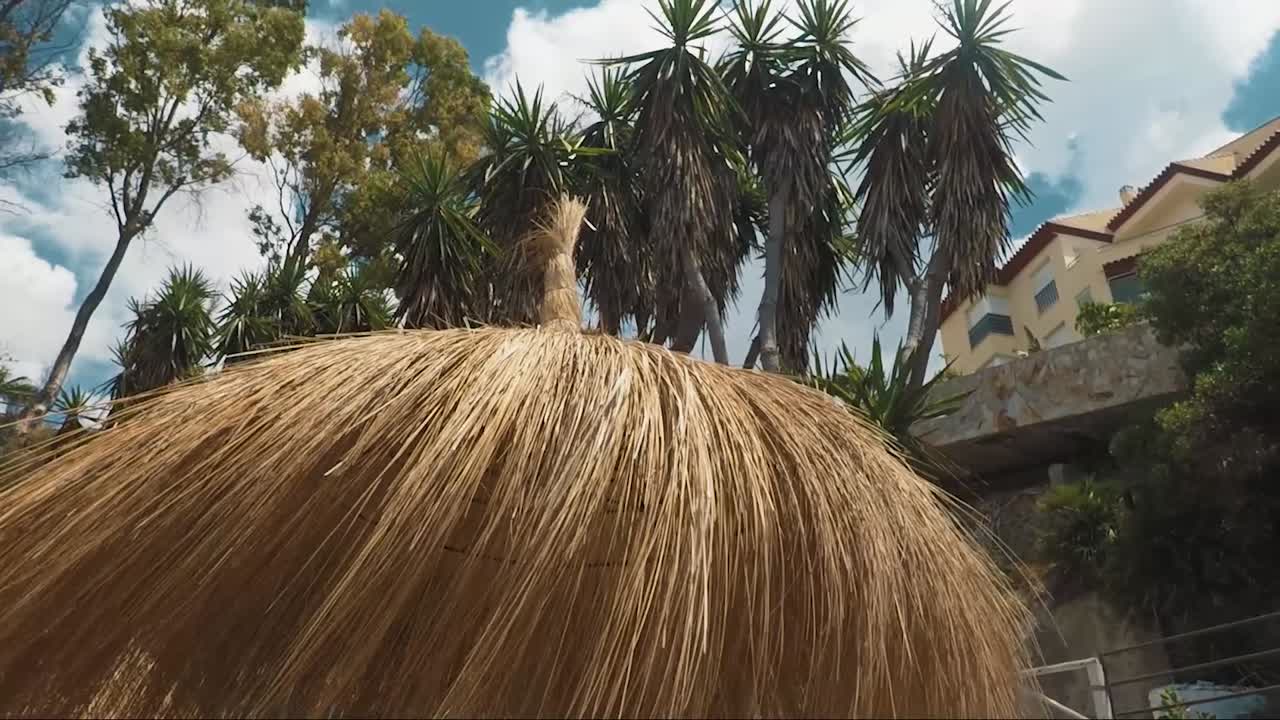 sombrilla en la playa y casa en el acantilado