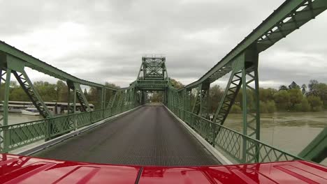 red vehicle traveling over big steel bridge