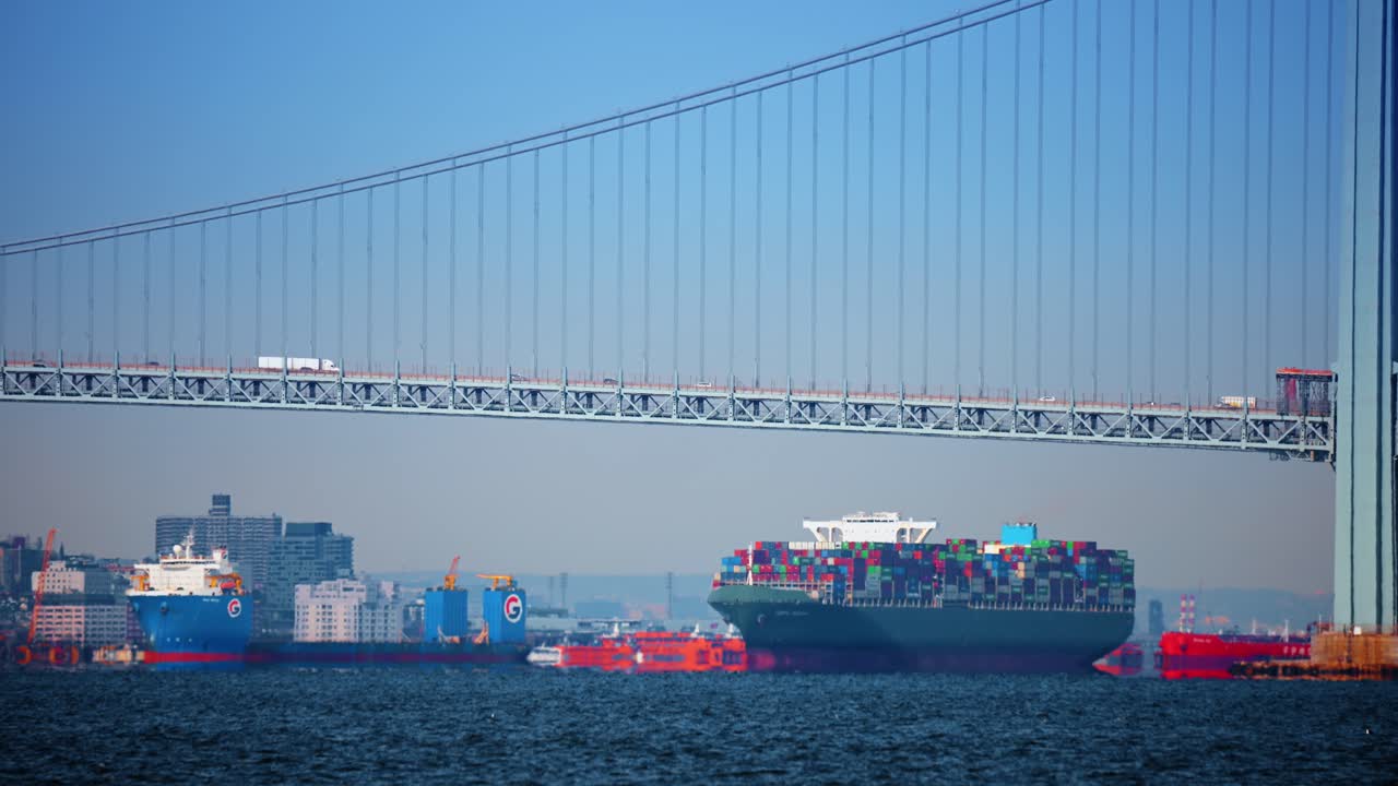 New York, USA, 24 December 2025: Cargo ship under Verrazzano Narrows. Large container ship sails below the Verrazzano Narrows Bridge, New York