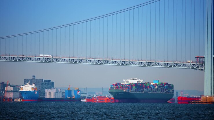 New York, USA, 24 December 2025: Cargo ship under Verrazzano Narrows. Large container ship sails below the Verrazzano Narrows Bridge, New York
