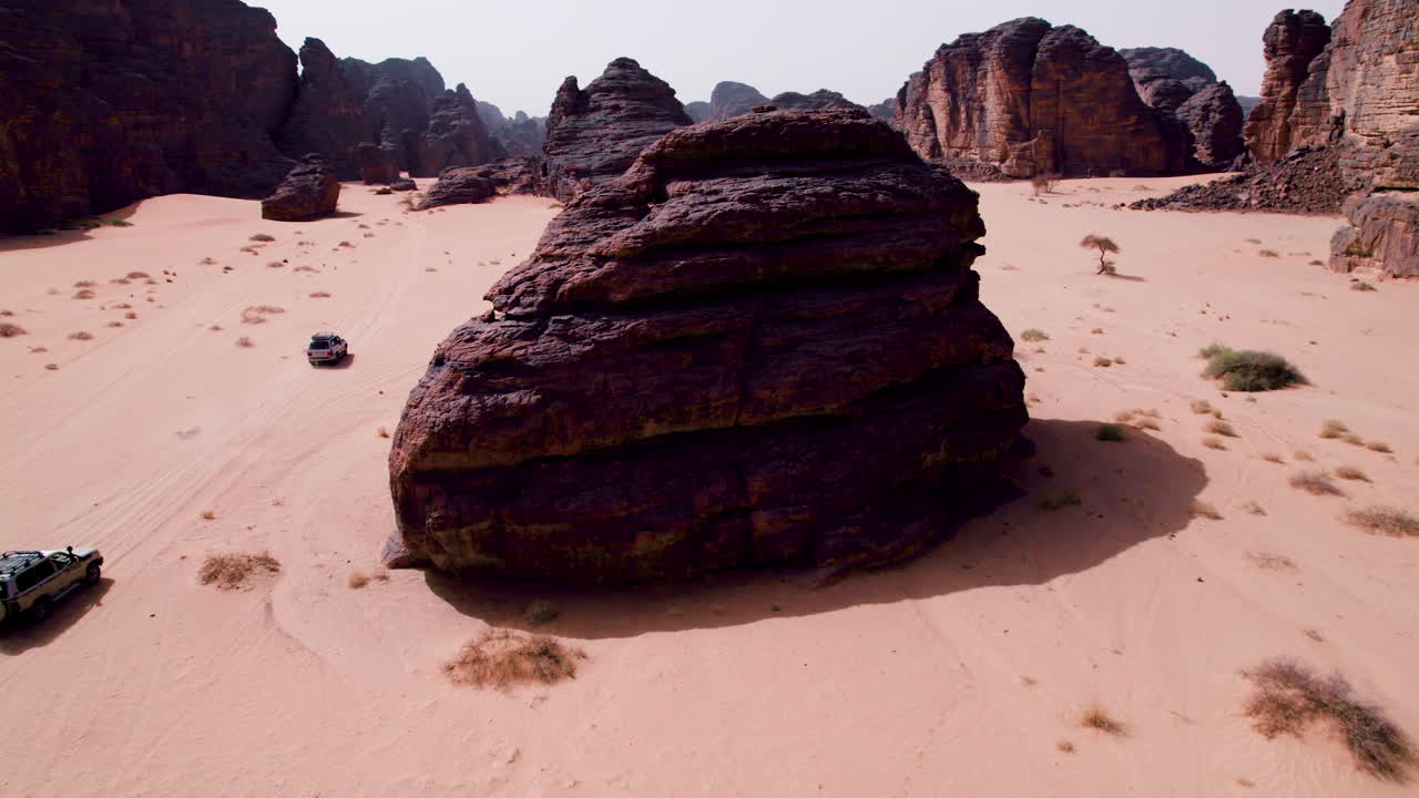 Auto SUV che navigano nel deserto del Sahara attraverso formazioni rocciose