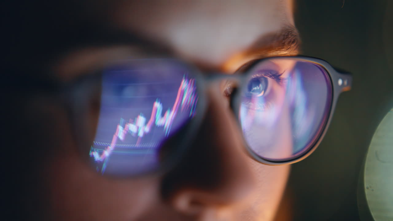 Eyes glasses reflecting diagrams at dark place closeup. Concentrated trader face