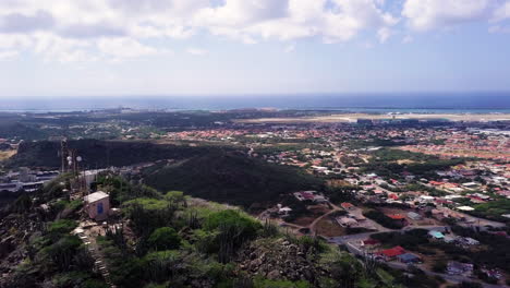 Vista-Aérea-De-Los-Automóviles-Que-Conducen-En-El-Extremo-Sur-De-Aruba-Desde-La-Cima-De-La-Montaña-Hooiberg