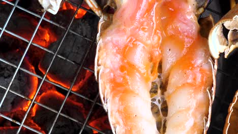 delicious lobster tail is cooking on blazing hot charcoal, static top-down view