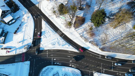 cars driving and waiting for a traffic light on a black intersection cleared from snow on a sunny day