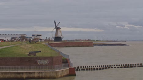 windmills in the city province of europe netherlands holland dutch with sea ocean water and rural view