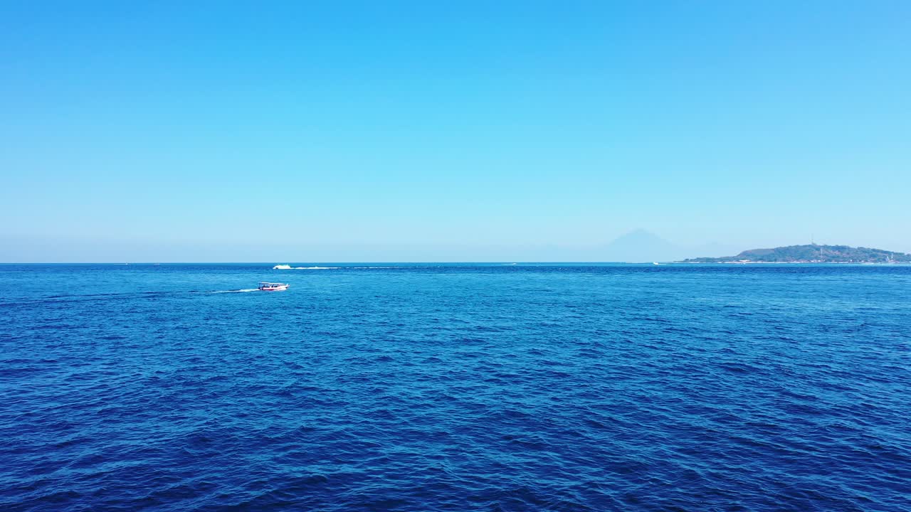 Boats sailing in the deep ocean. Small island in the distance. summer holiday background