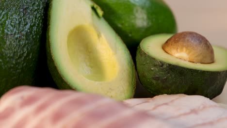 various high-fat foods including nuts, seeds, olive oil, butter, avocado, and bacon are displayed on a wooden surface with smooth camera panning and natural lighting