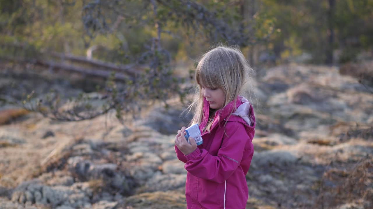 retrato de una niña de cuatro años parada en el bosque sosteniendo un juguete nuevo, tiro medio estático en cámara lenta