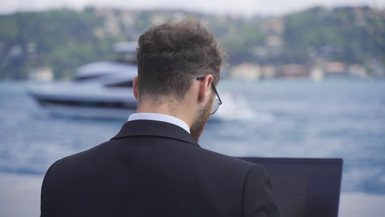 Uomo d'affari che lavora al computer portatile di fronte al mare