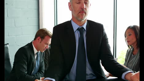 hombre haciendo yoga en la mesa mientras el equipo de negocios discute