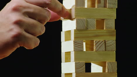 duas pessoas se revezam puxando barras de madeira da torre brincando em jenga