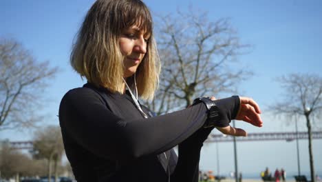 smiling sporty girl checking wrist watch in park