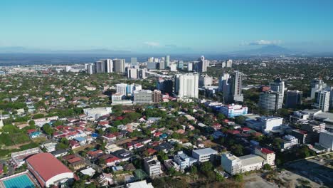 Flyover-drone-shot-of-panoramic-Philippine-cityscape-with-rural-neighborhoods,-modern-buildings-and-stunning-skyline-in-Alabang,-Muntinlupa-City