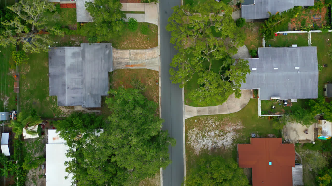 Straight down aerial establishing of residential street in Tampa Florida surrounded by green trees, tracking over suburban neighborhood