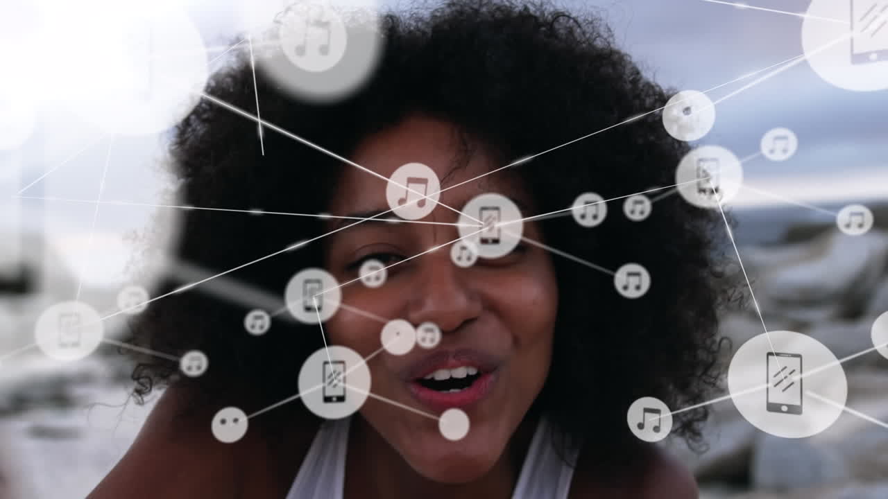 red de iconos digitales contra el retrato de una mujer afroamericana soplando besos en la playa