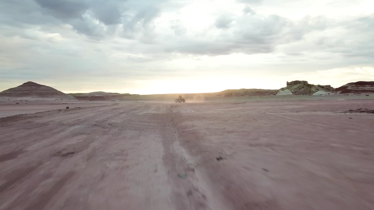 Vista aerea dinamica di strada sterrata e quad ATV nel deserto dello Utah sotto un cielo drammatico POV