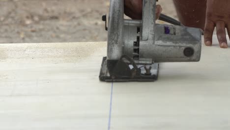 construction worker cutting wood planks with circular electric saw outdoors