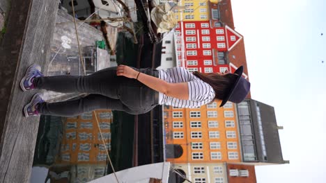 Woman-in-hat-standing-by-the-promenade-in-Nyhavn-turns-back-smiling-at-camera-in-Copenhagen