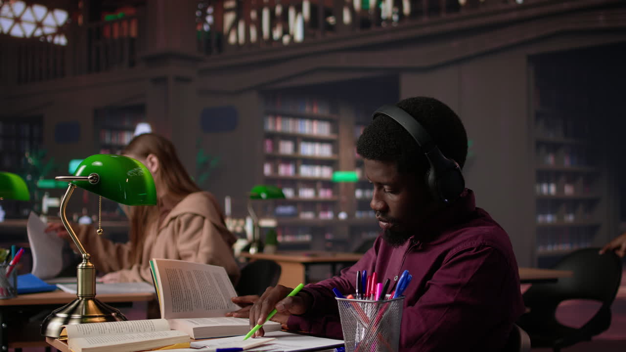 Vertical video male student listening to ambient study music on headset and collecting data