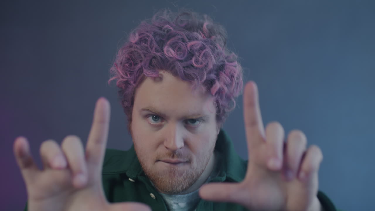 Man with pink hair, framing a shot with his hands