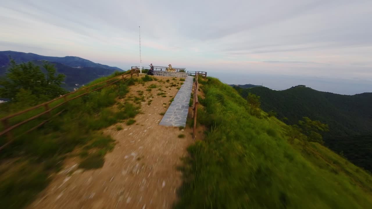 Aerial shot of a lush green mountain with an FPV drone capturing the scene