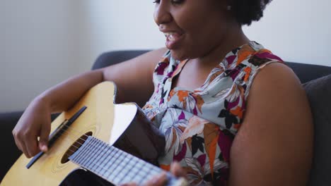 Plus-size-african-american-woman-singing-and-playing-acoustic-guitar