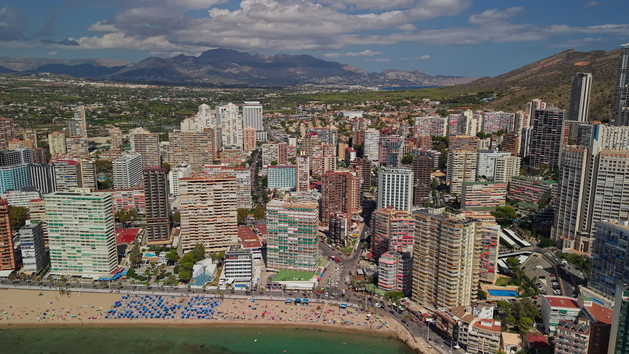 Vista aerea di una vivace città costiera con spiaggia e montagne.