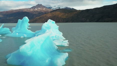 Vista-Aérea-Baja-Volando-Sobre-Icebergs-En-Un-Lago-Glacial-En-El-Desierto-Montañoso-De-La-Patagonia,-Chile