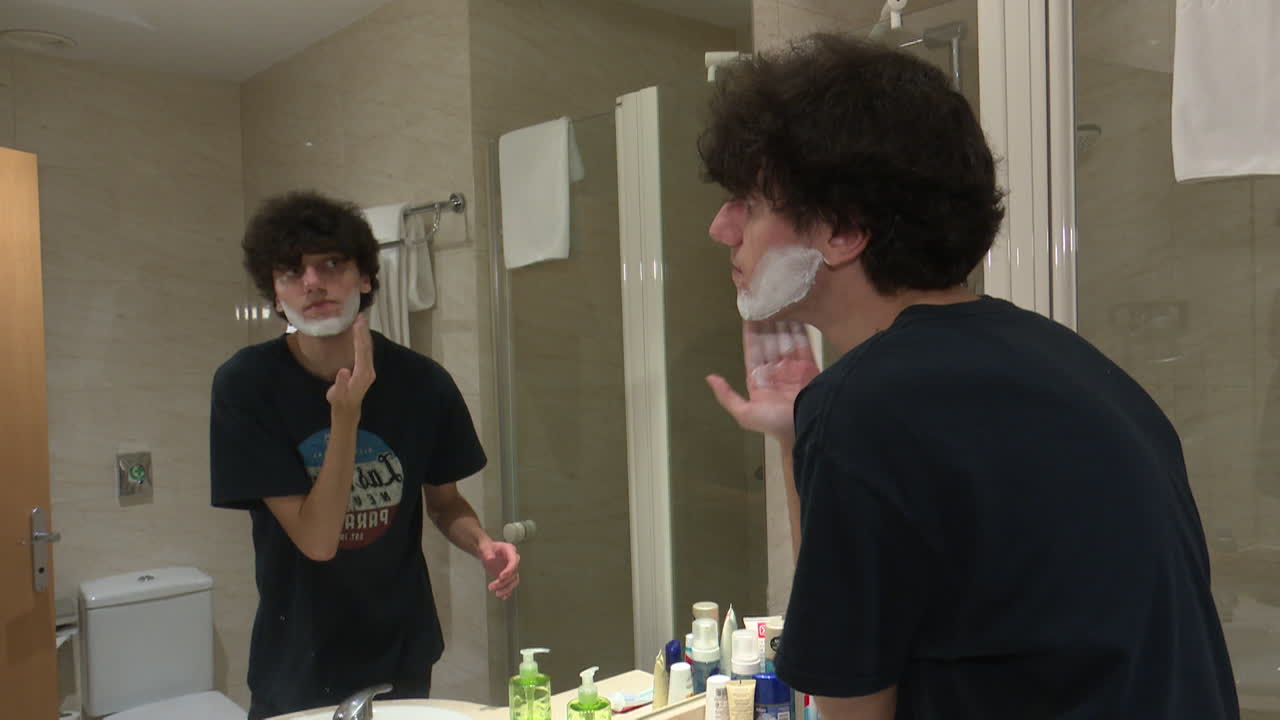 Teenager Shaving in a Hotel Bathroom