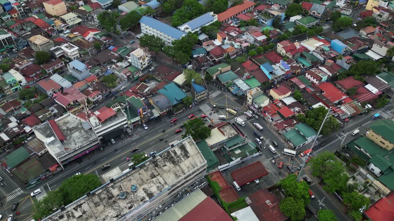 Aerial flyover shot of polluted cityscape, bustling streets, and dilapidated rooftops at Marikina City, Philippines.